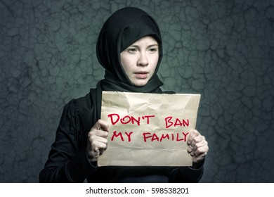 Muslim Girl In Black Hijab Holding A Poster With An Inscription DON'T BAN MY FAMILY Against A Wall With Cracks