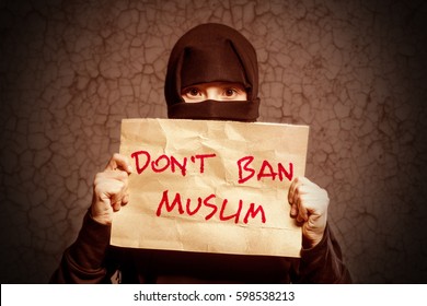 Muslim Girl In Black Hijab Holding A Poster With An Inscription DON'T BAN MUSLIM Against A Brown Wall With Cracks