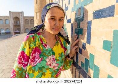 Muslim girl with a scarf on her head at the gate of the old mosque. Bukhara, Uzbekistan