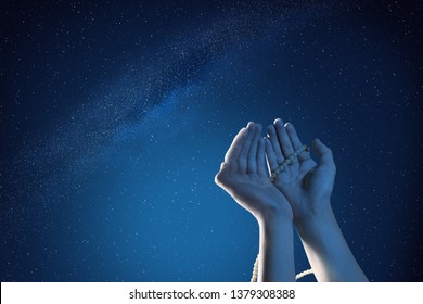 Muslim hands praying with prayer beads at outdoor with night scene background
