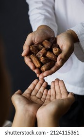 Muslim hands share a fistful of dates. ramadan kareem concept - Shutterstock ID 2124115361