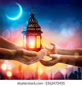 Muslim Holy Month Ramadan Kareem - Hand Give To Kid Arabic Lantern Glowing At Evening With Abstract Defocused Lights - Eid Ul Fitr - Shutterstock ID 2262473435