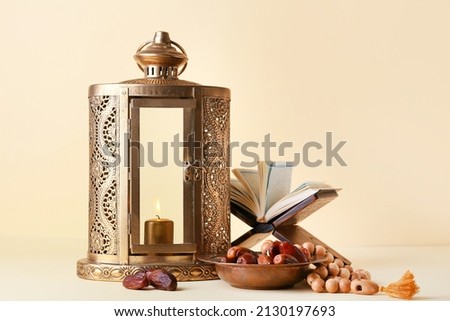 Muslim lantern, dates, Koran and tasbih on color background