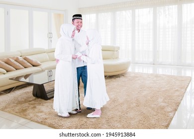 Muslim Little Girl Getting Money Envelope From Her Parents At Eid Mubarak While Standing Together In Living Room At Home