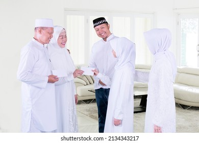 Muslim Little Girl Getting Money Envelope While Visiting Grandparents At Eid Celebration. Shot At Home