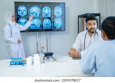 Muslim male and female doctors in medical uniforms was sitting at the patient's examination table and was examining and talking about the patient with a smiling and worried face in hospital. - Shutterstock ID 2359978017