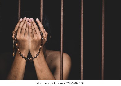 Muslim Man Inmate In Prison With Bead In Hand Raises His Hand To Make A Wish And Pray On Black Background.concept For Prisoner,sadness,detain,erroneousness