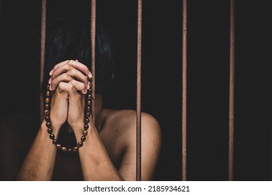 Muslim Man Inmate In Prison With Bead In Hand Raises His Hand To Make A Wish And Pray On Black Background.concept For Prisoner,sadness,detain,erroneousness