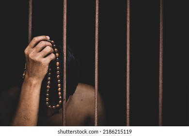 Muslim Man Inmate In Prison With Bead In Hand Raises His Hand To Make A Wish And Pray On Black Background.concept For Prisoner,sadness,detain,erroneousness