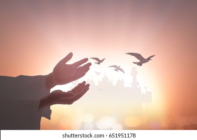 Muslim man open empty hands with palms up with birds flying over blurred mosque on sunset background - Shutterstock ID 651951178