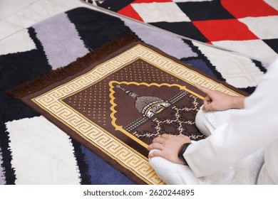 Muslim man praying on a sajjadah (prayer mat) during salah, wearing white attire, hands resting on knees in a peaceful moment of worship. - Powered by Shutterstock - Get 15% off with code: PIKWIZARD15