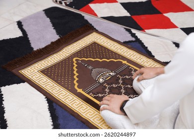 Muslim man praying on a sajjadah (prayer mat) during salah, wearing white attire, hands resting on knees in a peaceful moment of worship. - Powered by Shutterstock - Get 15% off with code: PIKWIZARD15