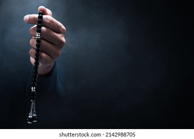 Muslim man praying with rosary beads
