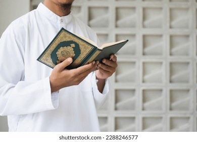 Muslim man reading holy Quran. Holy Quran in Hand with arabic text meaning of Al Quran