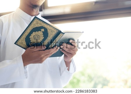 Muslim man reading holy Quran. Holy Quran in Hand with arabic text meaning of Al Quran