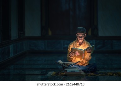 muslim man studying Islam holy quran book to understand and remember Allah god lesson in islamic mosque during holy ramadan period. Al quran book with written arabic calligraphy meaning of Al Quran - Shutterstock ID 2162448713