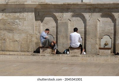 Muslim Mans Taking Ritual Ablution In Wudhu Station At Mosque In ISTANBUL - September, 2021. Faucets For Washing Hands And Feet Before The Prayer And Stones To Sit On Near Mosque In Islamic Culture. 