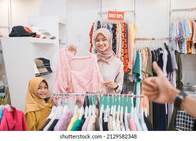 Muslim Mother Choosing Shirt With Daughter During Shopping At Fashion Shop