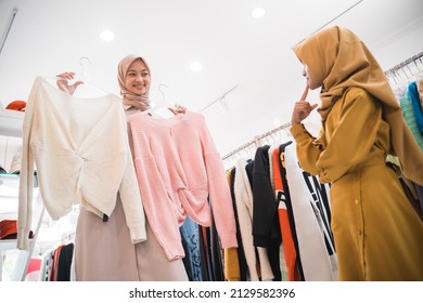 Muslim Mother Choosing Shirt With Daughter During Shopping At Fashion Shop