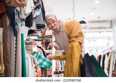 Muslim Mother Choosing Shirt With Daughter During Shopping At Fashion Shop