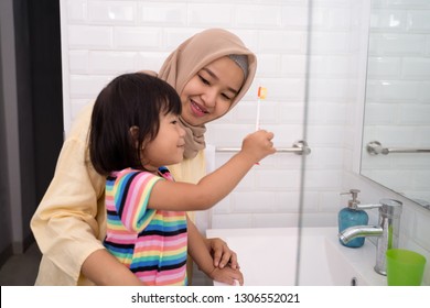 muslim mother and her daughter brushing teeth together before bed