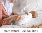 Muslim mother in hijab and cute little baby sleeping on bed at home, closeup