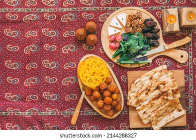 Muslim Ramadan Kareem Festive, Iranian Sweets, Zoolbia, Bamieh,dates And Walnut And Chees On Wooden Plate And Candles On A Traditional Red Termeh Background,month Fasting Culture.copy Space.