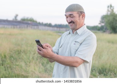 Muslim Senior Man Uses A Mobile Phone In A Siberian Village