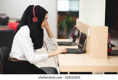 Muslim student girl using online education service. Young woman looking in laptop display watching training course and listening it with headphones. Modern study technology concept. - Powered by Shutterstock