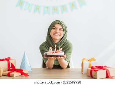 Muslim Teen Girl In Hijab Holding Delicious Birthday Cake At Table With Gift Boxes, Celebrating Festive Occasion At Home. Islamic Adolescent Having Yummy Dessert For Holiday, Enjoying Party