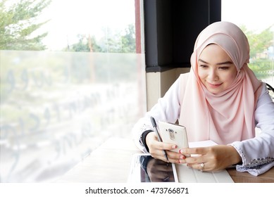 Muslim Teen Wearing A Head Scarf Using A Phone