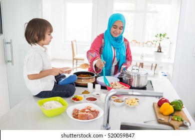 Muslim traditional woman with little son in modern white kitchen - Powered by Shutterstock