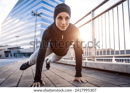 Muslim urban runner training in the city center. Beautiful woman doing sport in the early morning