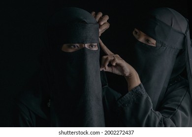 Muslim Woman In Black Nigab Dressing Up For Her Friend Or Younger Sister On Black Background, Selective Focus