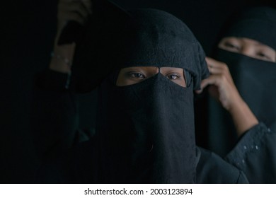 Muslim Woman In Black Nigab Dressing Up For Her Friend Or Younger Sister On Black Background, Selective Focus