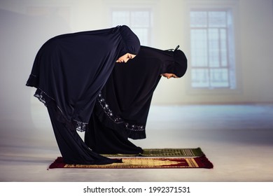 Muslim Woman In Black Traditional Dress Praying Together In Mosque Background. Bend Down, Side View, Standing