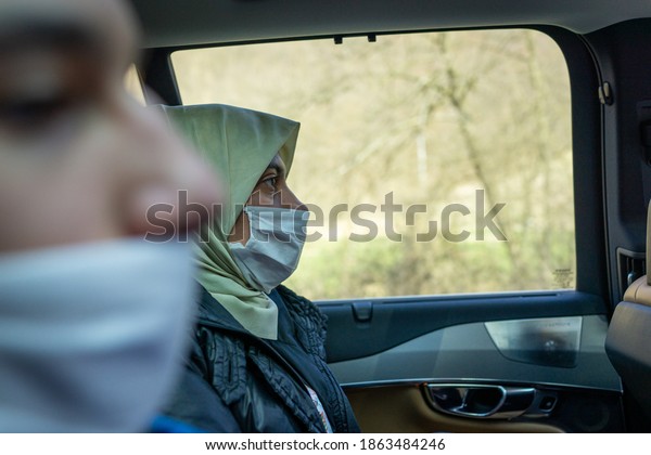 Muslim woman in car with\
mask