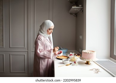 Muslim woman cooks dessert cake at home kitchen, arabian young model in hijab and abaya - Powered by Shutterstock