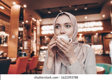 Muslim Woman Drinks Coffee In A Cafe At A Table