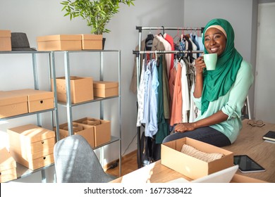 Muslim Woman Fashion Designer In Her Shop. Women, Owener Of Small Business Packing Product In Boxes, Preparing It For Delivery. Woman Packing Item That She Sells Online