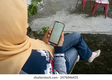 Muslim Woman Hand Holding Mobile Phone Shopping Online Looking At Empty Display Sitting Outdoors  - Powered by Shutterstock