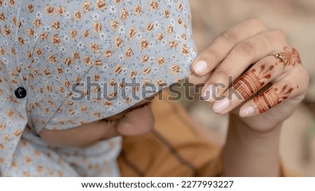 Muslim woman with henna tattoo on her hands outdoors, smile face with Hijab closeup
