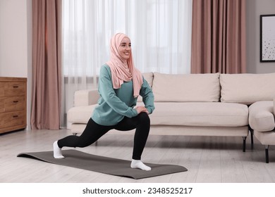 Muslim woman in hijab doing exercise on fitness mat at home. Space for text - Powered by Shutterstock