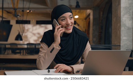 Muslim woman in hijab female business employer consultant office manager Arabian smiling businesswoman talk mobile phone consult at workplace happy positive islamic girl looking at laptop online order - Powered by Shutterstock