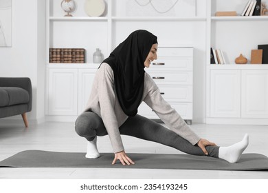 Muslim woman in hijab stretching on fitness mat at home - Powered by Shutterstock