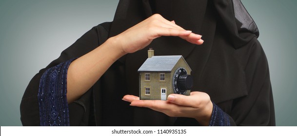 a muslim woman holding a small house model in her hand in Saudi Arabia Gulf Middle East