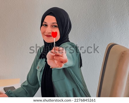 A Muslim woman holds a lollipop in her hand in her home office. High quality photo