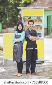 muslim woman and man small business owner standing proudly in front of their food stall. selling halal product