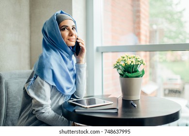 Muslim Woman On Break Using Mobile Phone In cafe