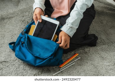 A Muslim woman prepares and packs her college supplies in to her backpack